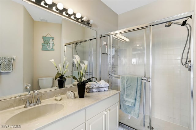 bathroom with a shower stall, vanity, and toilet