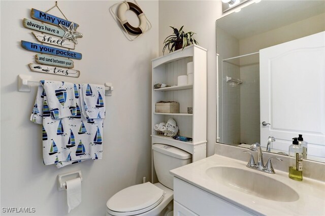 bathroom with a tile shower, vanity, and toilet