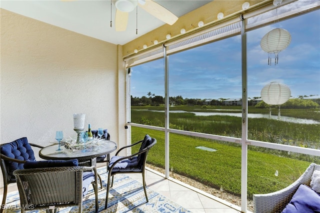 sunroom with ceiling fan and a water view