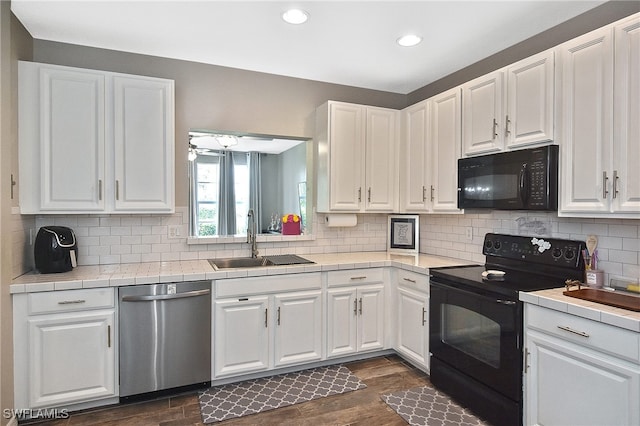 kitchen with tile countertops, white cabinetry, sink, black appliances, and dark hardwood / wood-style floors