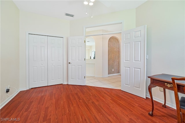 bedroom with a closet, light hardwood / wood-style floors, stainless steel refrigerator, and ceiling fan