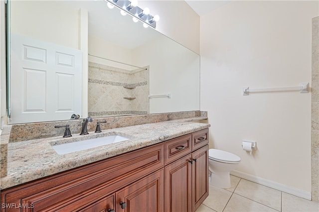 bathroom with vanity, toilet, a tile shower, and tile patterned floors