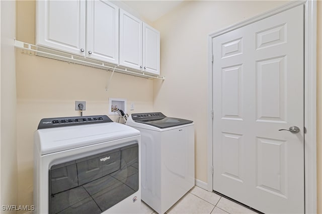 clothes washing area featuring light tile patterned floors, washing machine and dryer, and cabinets