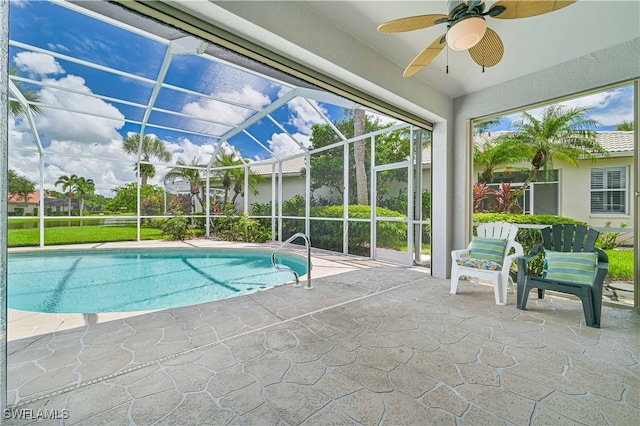 view of swimming pool with ceiling fan, glass enclosure, and a patio area