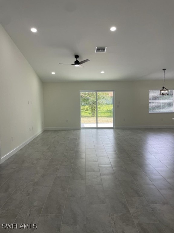 spare room with ceiling fan with notable chandelier