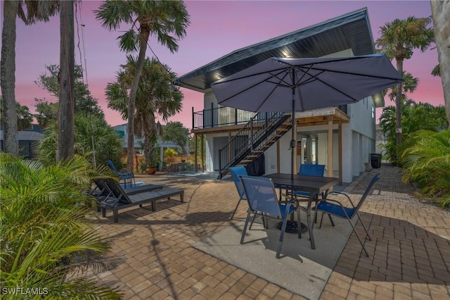 patio terrace at dusk featuring outdoor dining space and stairway