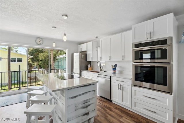 kitchen with appliances with stainless steel finishes, a breakfast bar, white cabinets, and light countertops