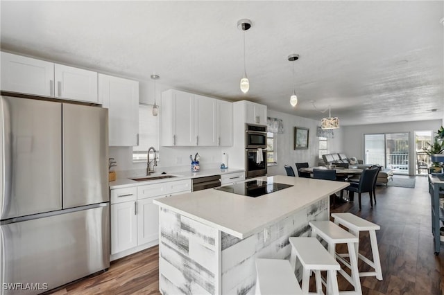 kitchen with a sink, white cabinetry, open floor plan, light countertops, and black appliances