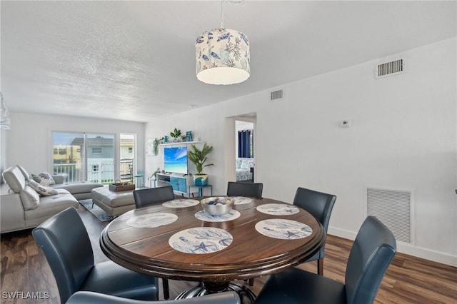 dining room featuring a textured ceiling, dark wood finished floors, visible vents, and baseboards