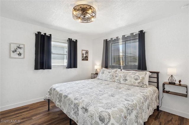 bedroom with baseboards, dark wood finished floors, and a textured ceiling