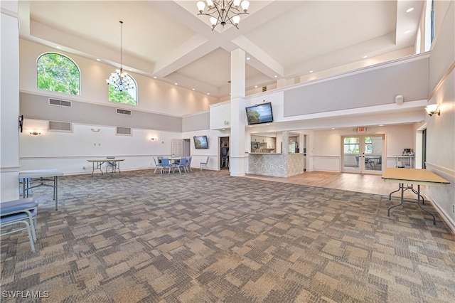 unfurnished living room featuring dark carpet, a towering ceiling, and an inviting chandelier