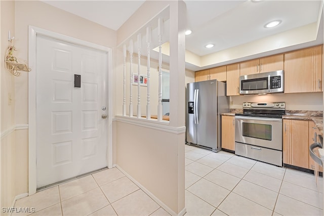 kitchen featuring light tile patterned floors, light brown cabinets, and stainless steel appliances