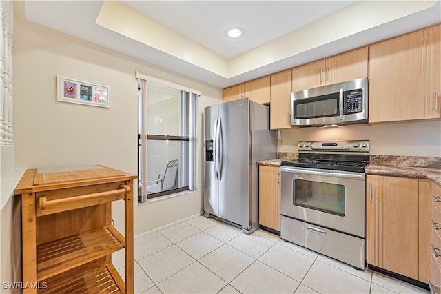 kitchen with light tile patterned floors, appliances with stainless steel finishes, and light brown cabinets