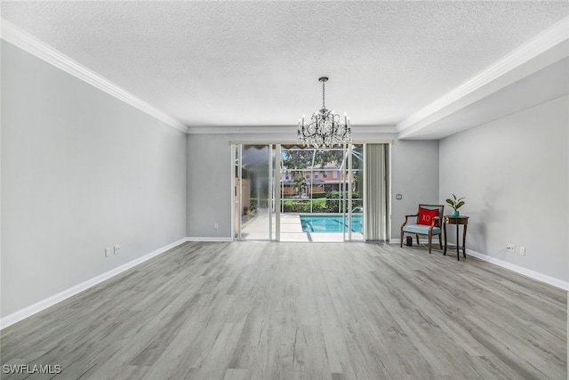 interior space with a textured ceiling, a notable chandelier, wood finished floors, and baseboards