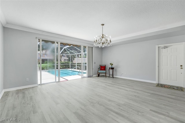 unfurnished room with a sunroom, baseboards, a textured ceiling, and wood finished floors