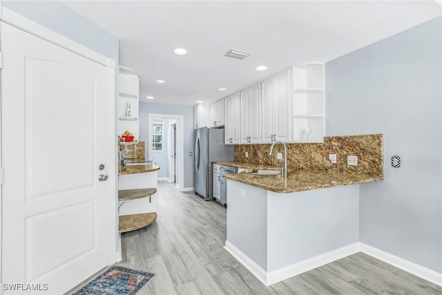 kitchen featuring stainless steel appliances, a sink, backsplash, open shelves, and dark stone countertops