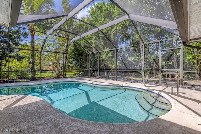 view of swimming pool featuring glass enclosure and a patio