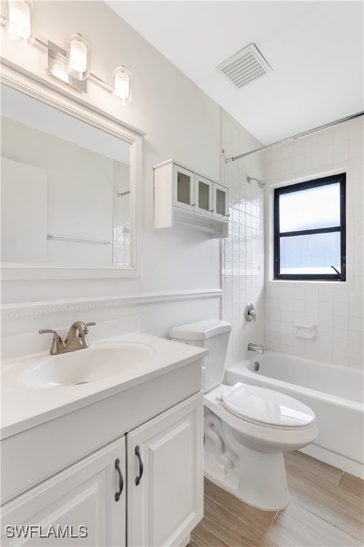 full bathroom featuring tiled shower / bath, toilet, wood-type flooring, and vanity