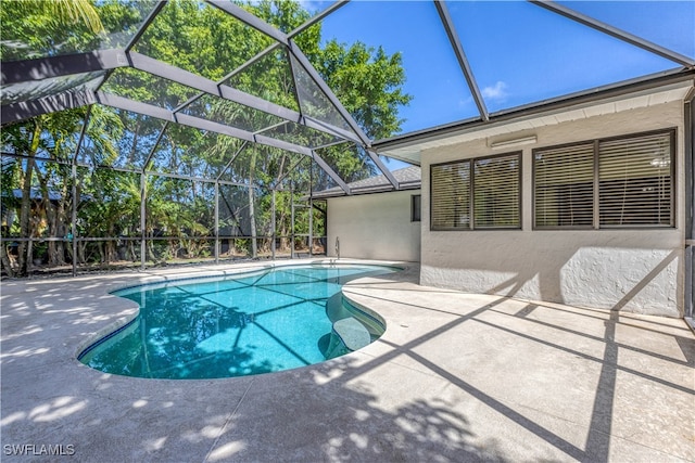 view of pool featuring glass enclosure and a patio area