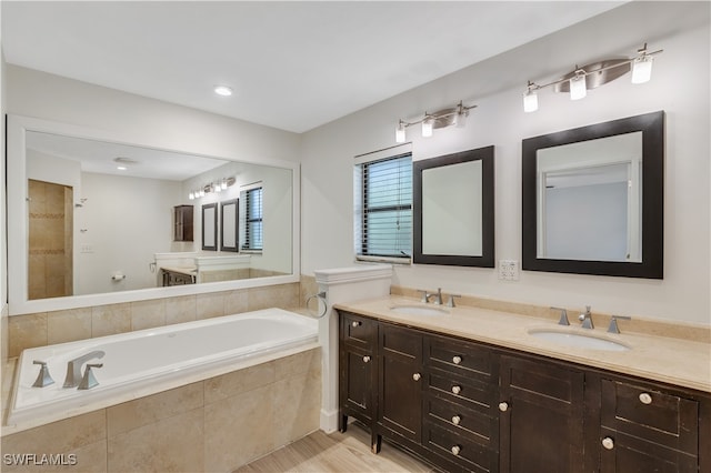 bathroom featuring vanity and tiled bath