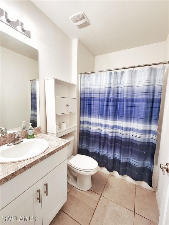 bathroom with tile patterned floors, toilet, curtained shower, and vanity