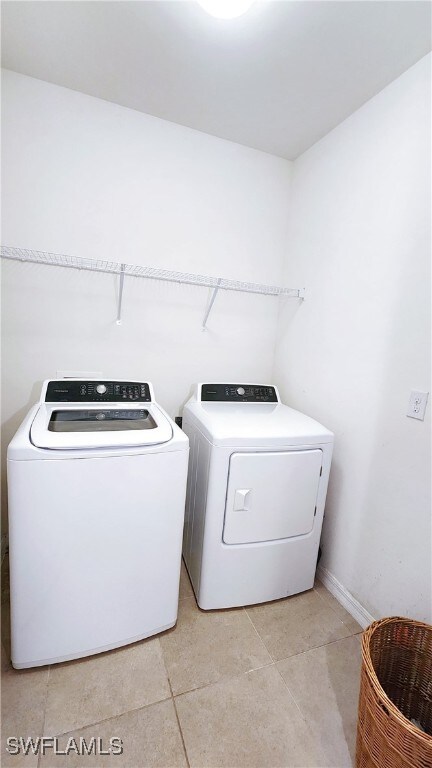 clothes washing area with light tile patterned floors and washer and dryer