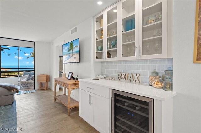 2777 W Gulf Dr Unit 109, Sanibel, FL 33957 - bar area featuring wine cooler, backsplash, light wood-type flooring, and expansive windows
