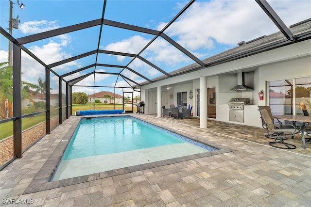 view of swimming pool with a grill, an outdoor kitchen, a patio, and a lanai