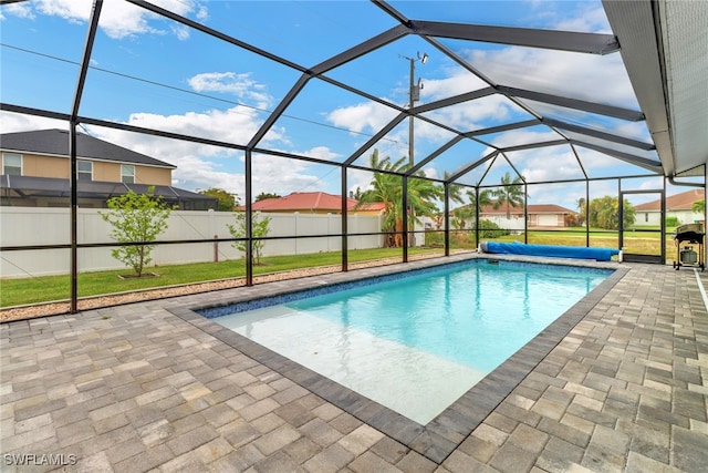 view of swimming pool featuring a yard, a patio, and glass enclosure