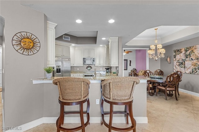 2090 W First St Unit 2007, Fort Myers, FL 33901 - kitchen featuring visible vents, light stone countertops, a breakfast bar area, appliances with stainless steel finishes, and a peninsula
