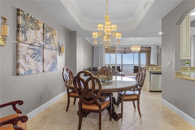 dining area featuring crown molding, a notable chandelier, a tray ceiling, and light tile patterned flooring