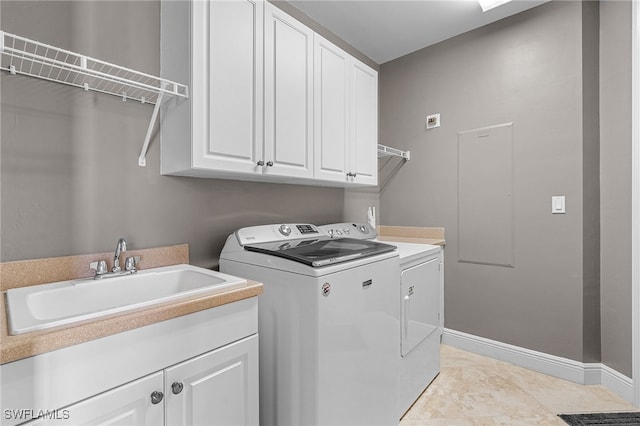 clothes washing area featuring light tile patterned floors, cabinets, washer and dryer, and sink