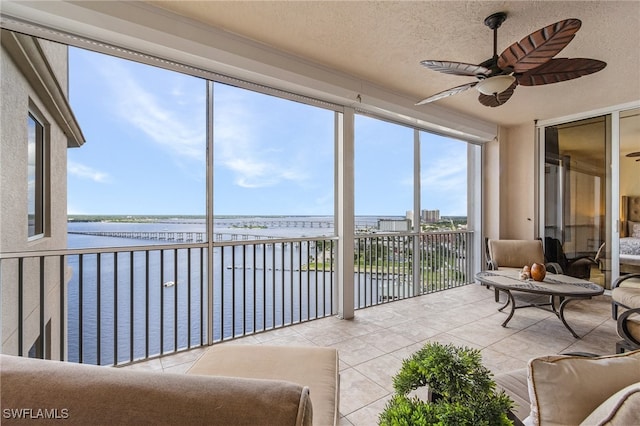 sunroom featuring a water view and ceiling fan