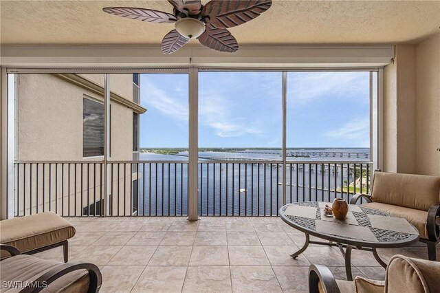 sunroom featuring a water view and ceiling fan