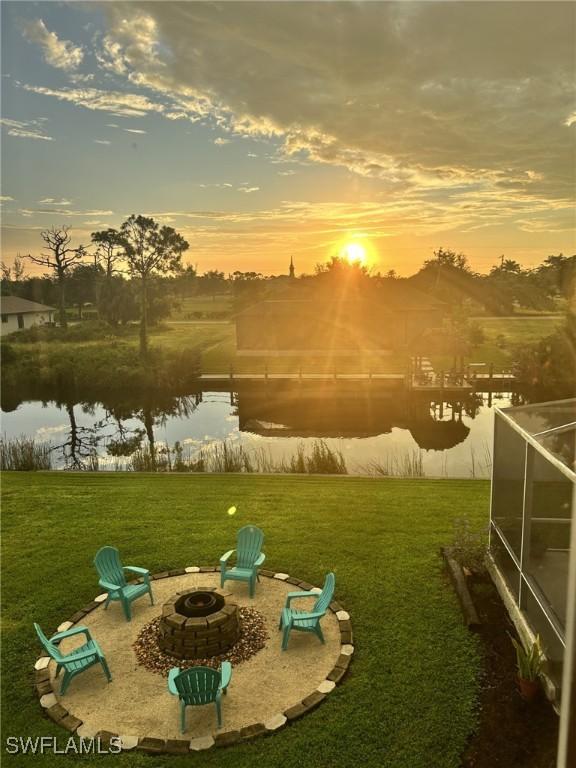 exterior space with a patio, a water view, glass enclosure, and an outdoor fire pit