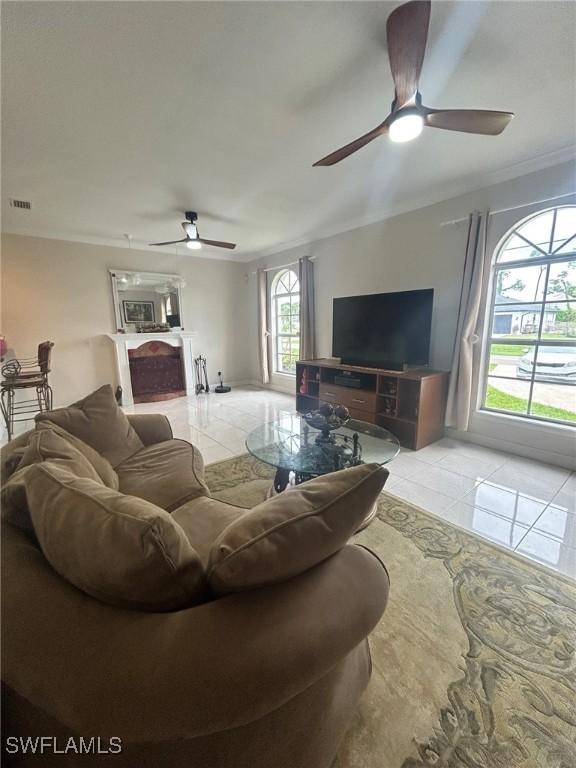 living room featuring light tile patterned floors, ornamental molding, and ceiling fan