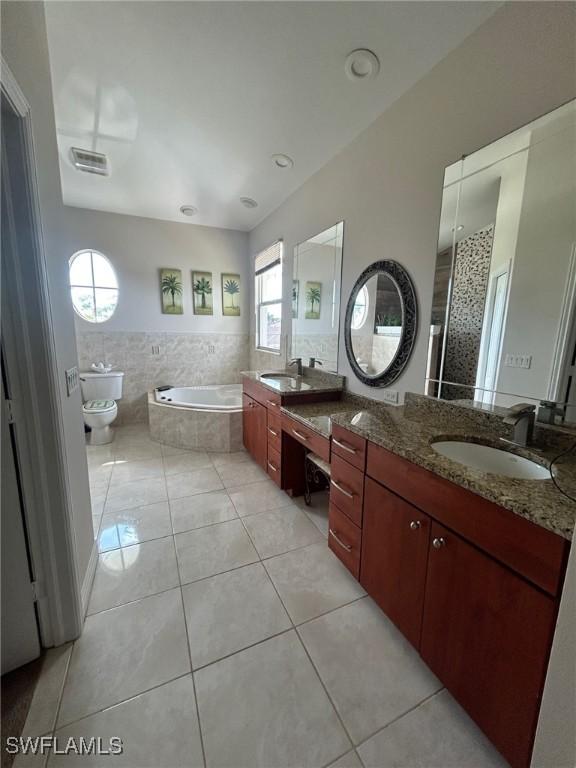 bathroom featuring vanity, tiled tub, tile patterned floors, and toilet