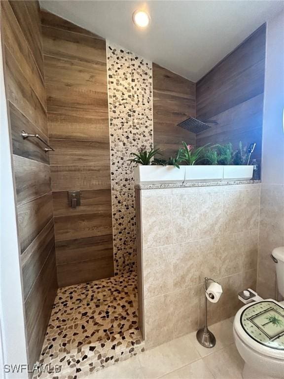 bathroom with lofted ceiling, tiled shower, tile patterned floors, and toilet