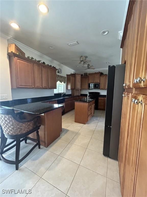 kitchen with a kitchen breakfast bar, a center island, light tile patterned floors, stainless steel appliances, and crown molding