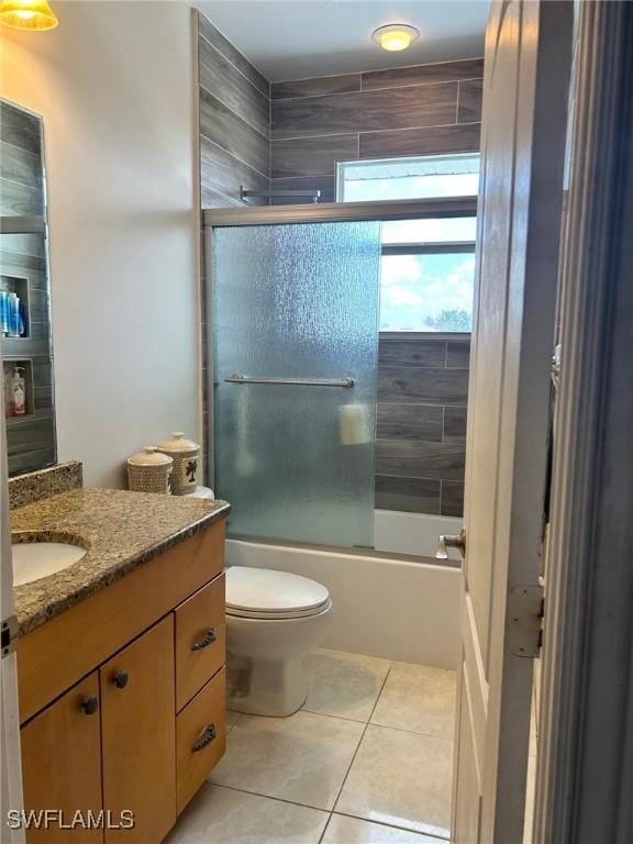 bathroom featuring toilet, shower / bath combination with glass door, vanity, and tile patterned floors