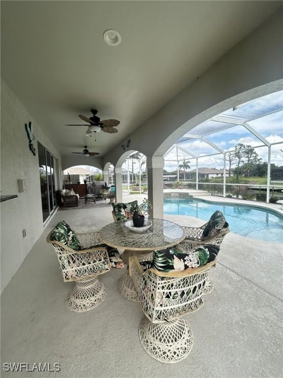 view of patio with a ceiling fan, a lanai, and an outdoor pool