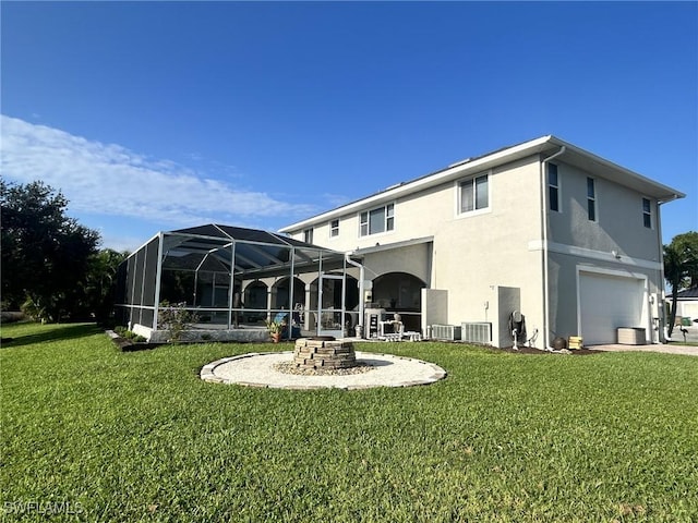 back of house featuring glass enclosure, an attached garage, a yard, a patio area, and stucco siding