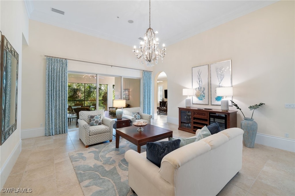 living room featuring light tile patterned floors, ornamental molding, a high ceiling, and an inviting chandelier