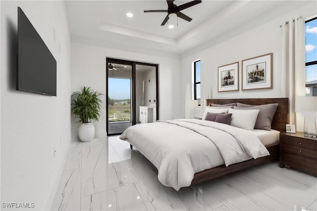 bedroom featuring multiple windows, access to outside, ceiling fan, and a tray ceiling