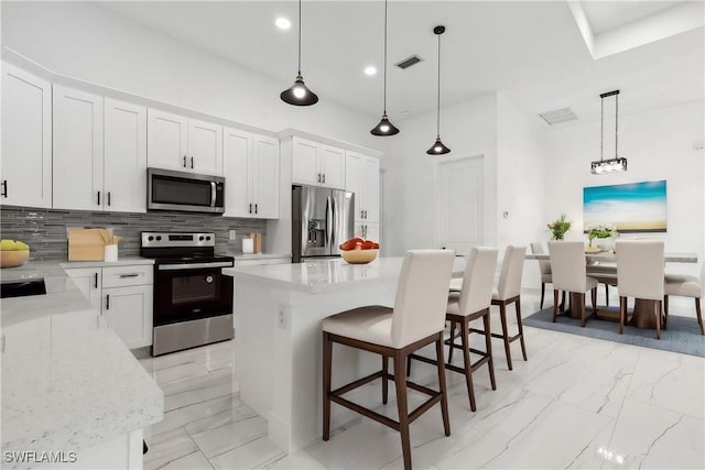 kitchen with pendant lighting, a center island, white cabinetry, and stainless steel appliances