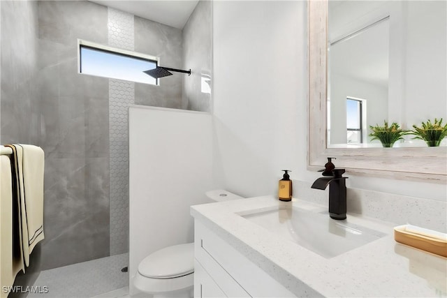 bathroom with toilet, vanity, and tiled shower