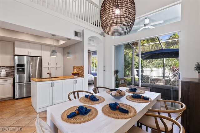 tiled dining room featuring a towering ceiling, ceiling fan, and sink