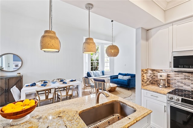 kitchen with stainless steel appliances, white cabinetry, decorative light fixtures, and sink