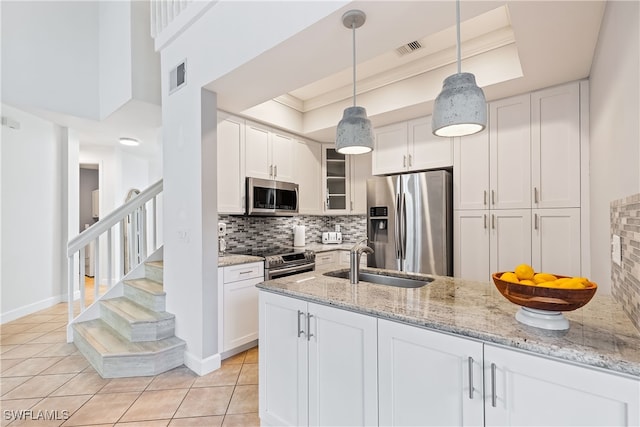 kitchen featuring decorative light fixtures, stainless steel appliances, sink, and white cabinetry