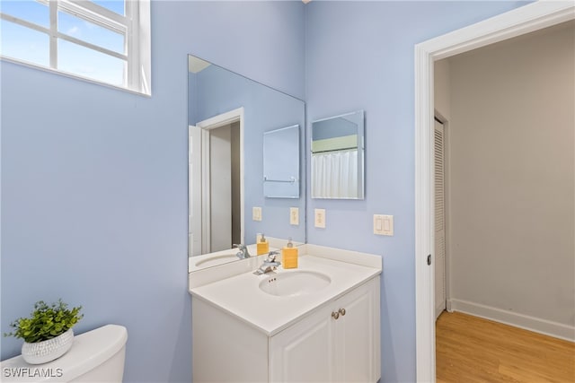 bathroom featuring wood-type flooring, vanity, and toilet